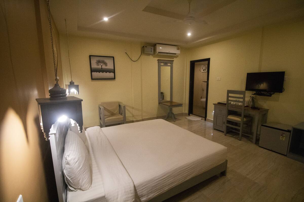 Une chambre à coucher comprenant un lit, un bureau, une chaise, un téléviseur et un appareil de climatisation.
