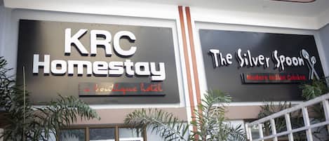 A hotel with signs for KRC Homestay and The Silver Spoon, indicating a boutique hotel and a restaurant offering modern Indian cuisine.