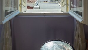 A room with a view of a coastal town through an open window. - Villa Maria (Syros)