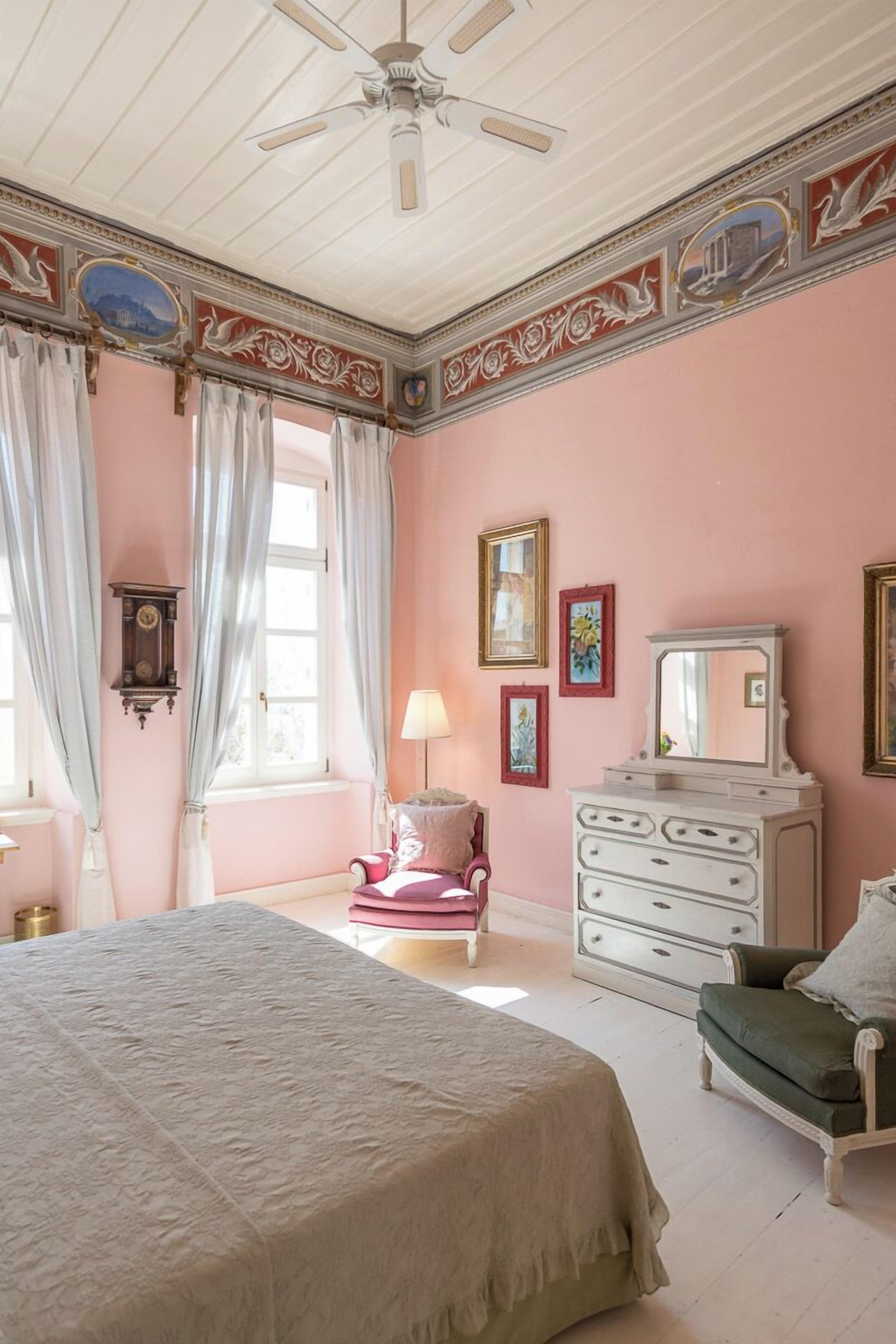 Un dormitorio con cama, cómoda, silla y ventilador de techo.