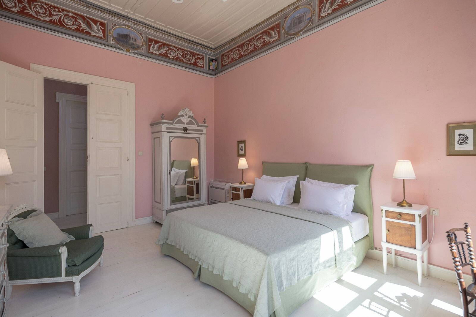 A bedroom with a bed, a chair, a dresser, and a mirror.