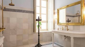 A bathroom with a white sink, gold-framed mirror, and a shower with a gold fixture.