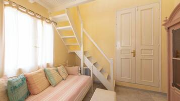 A room with a sofa, a staircase, and a door.