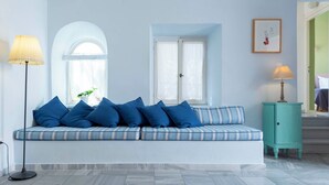 A room with a blue-striped sofa, a teal cabinet, and a floor lamp. - Villa Maria (Syros)