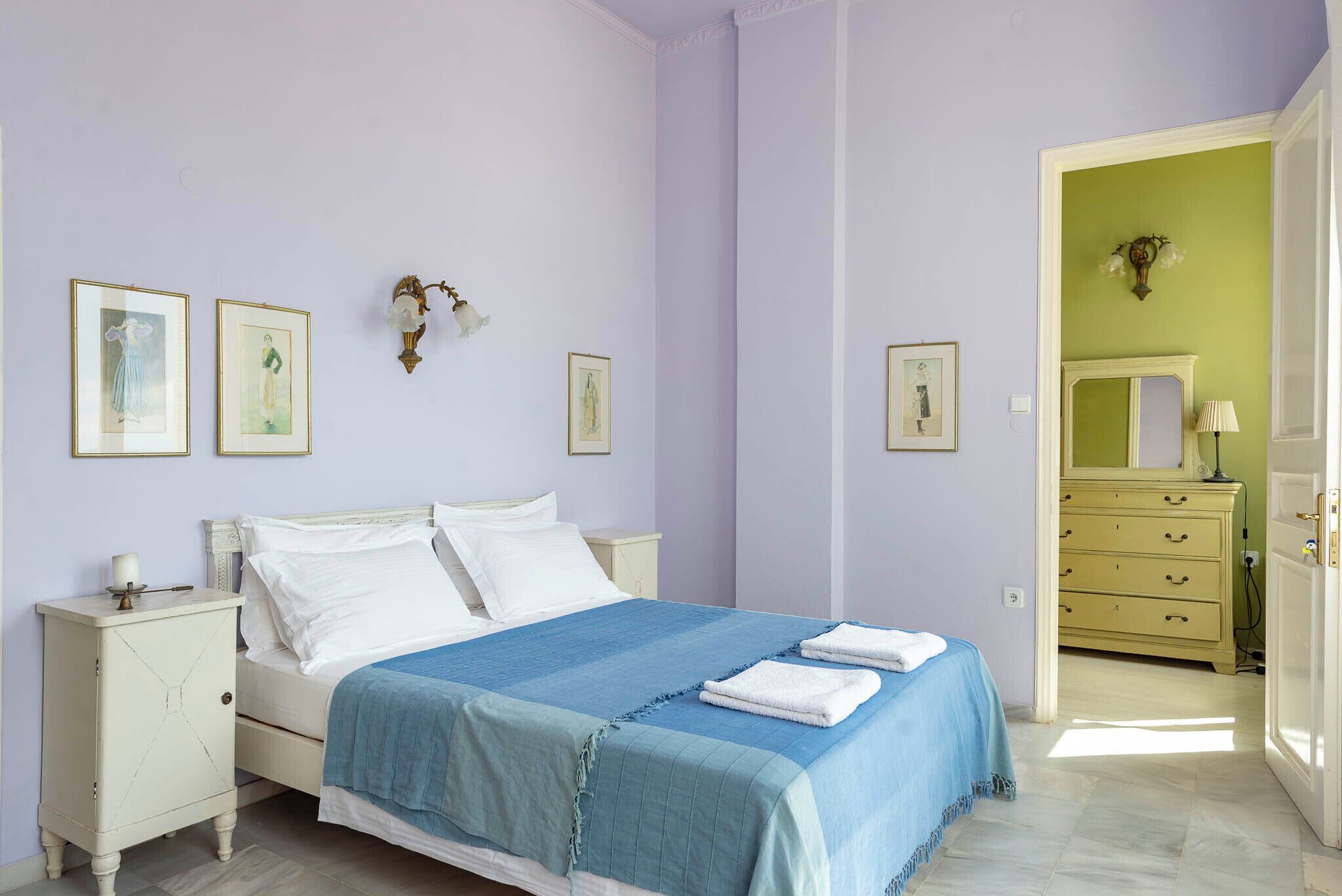 A bedroom with a bed, nightstands, a dresser, and framed pictures on the wall.