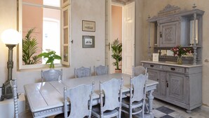 A dining room with a large table, six chairs, and a vintage cabinet with a mirror. - Villa Maria (Syros)