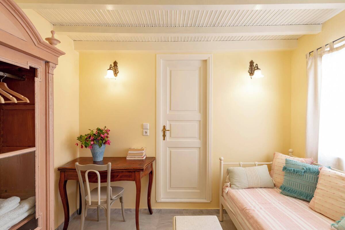 A room with a bed, a desk with a chair, a wardrobe, and a door.