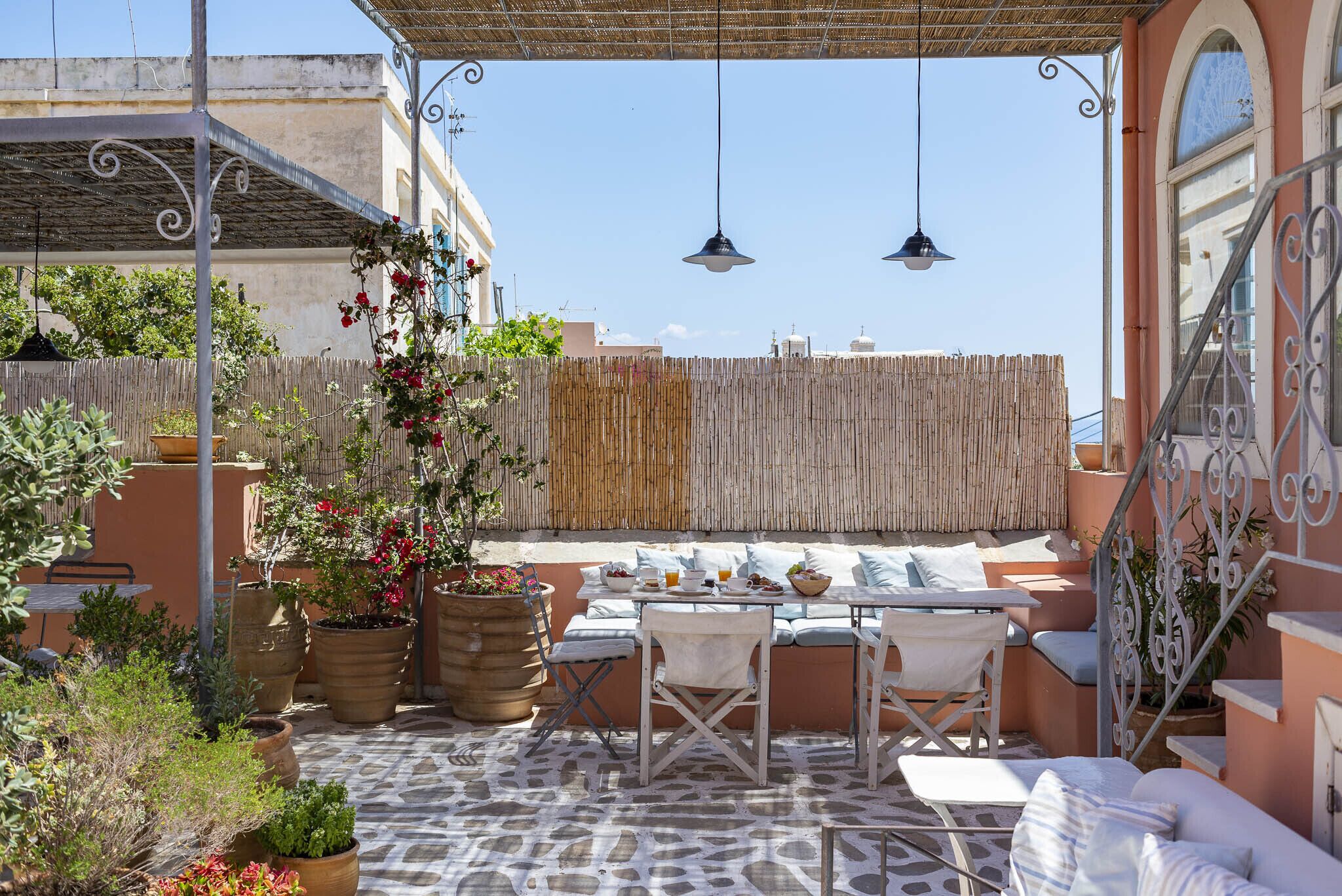 Une terrasse extérieure avec un espace salon, des tables et des plantes en pot.