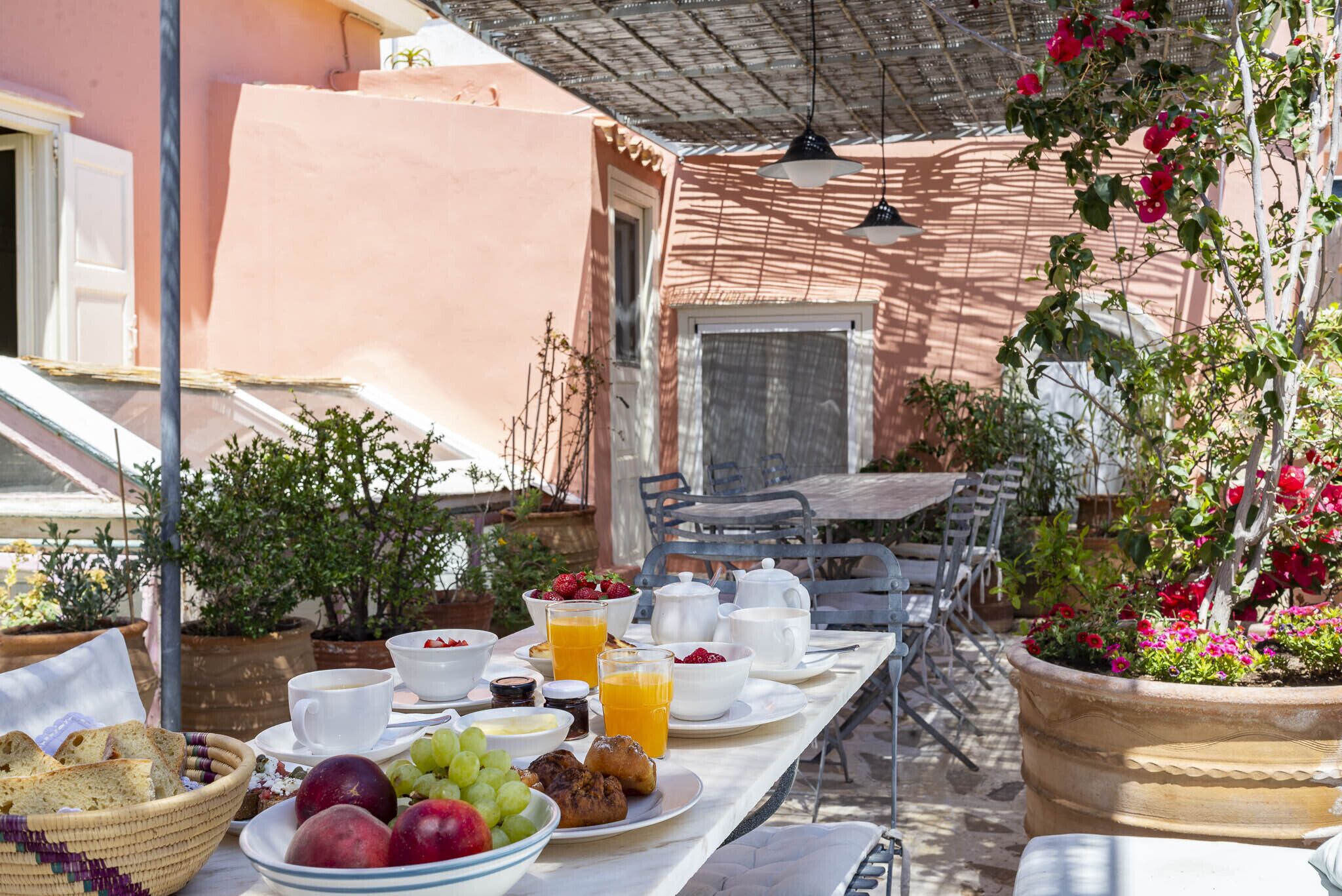 An outdoor breakfast setup with a table, chairs, and various breakfast items.