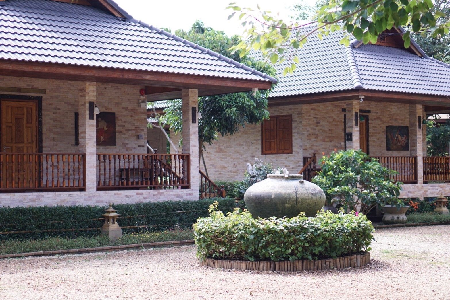 Ein traditionelles Gebäude mit einem Ziegeldach, hölzernen Balkonläbalen und einem Garten mit einer großen Steinfunktion.