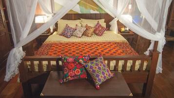 Una cama con dosel, almohadas coloridas y colcha estampada.