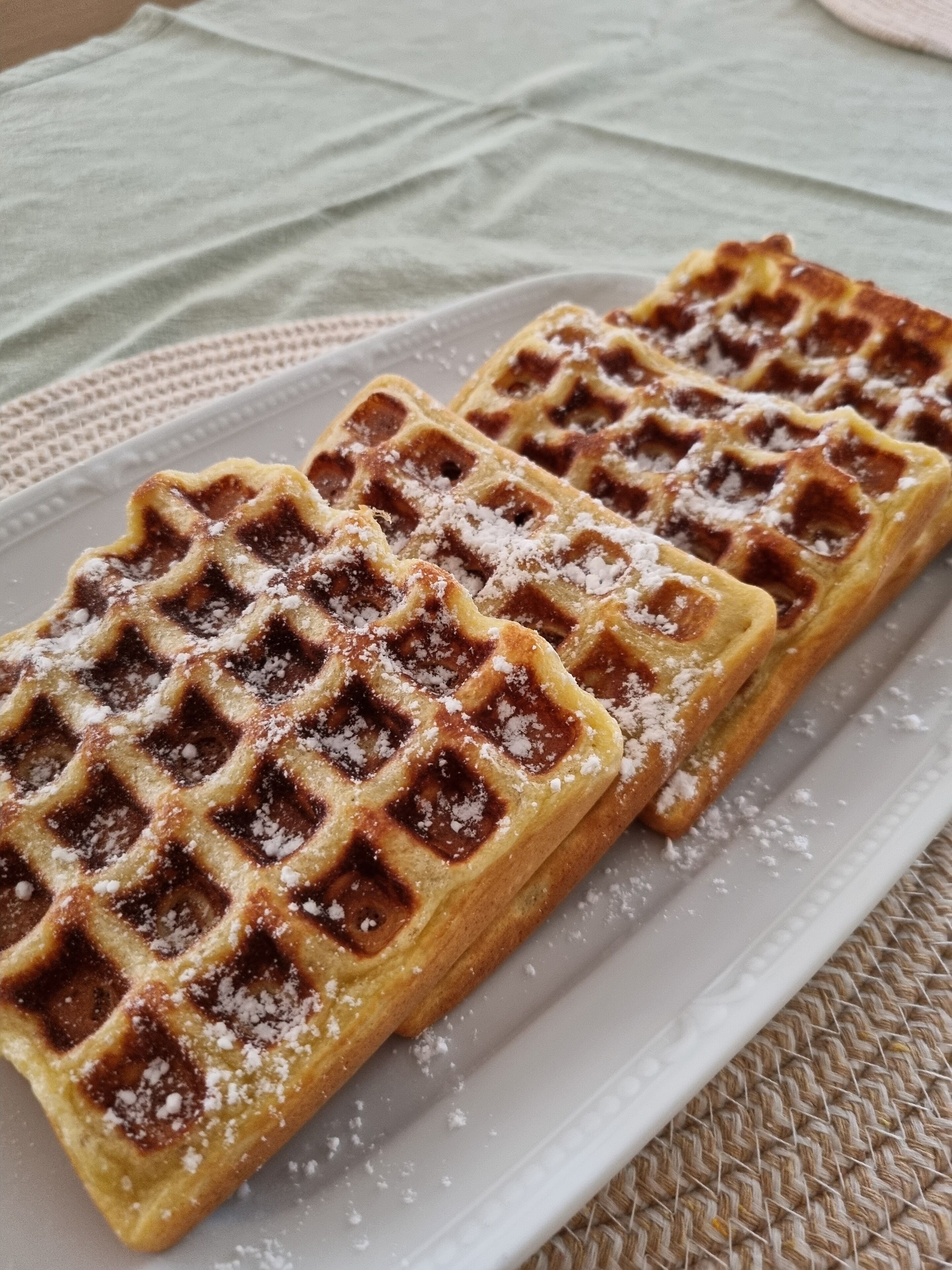 A plate of waffles with powdered sugar.