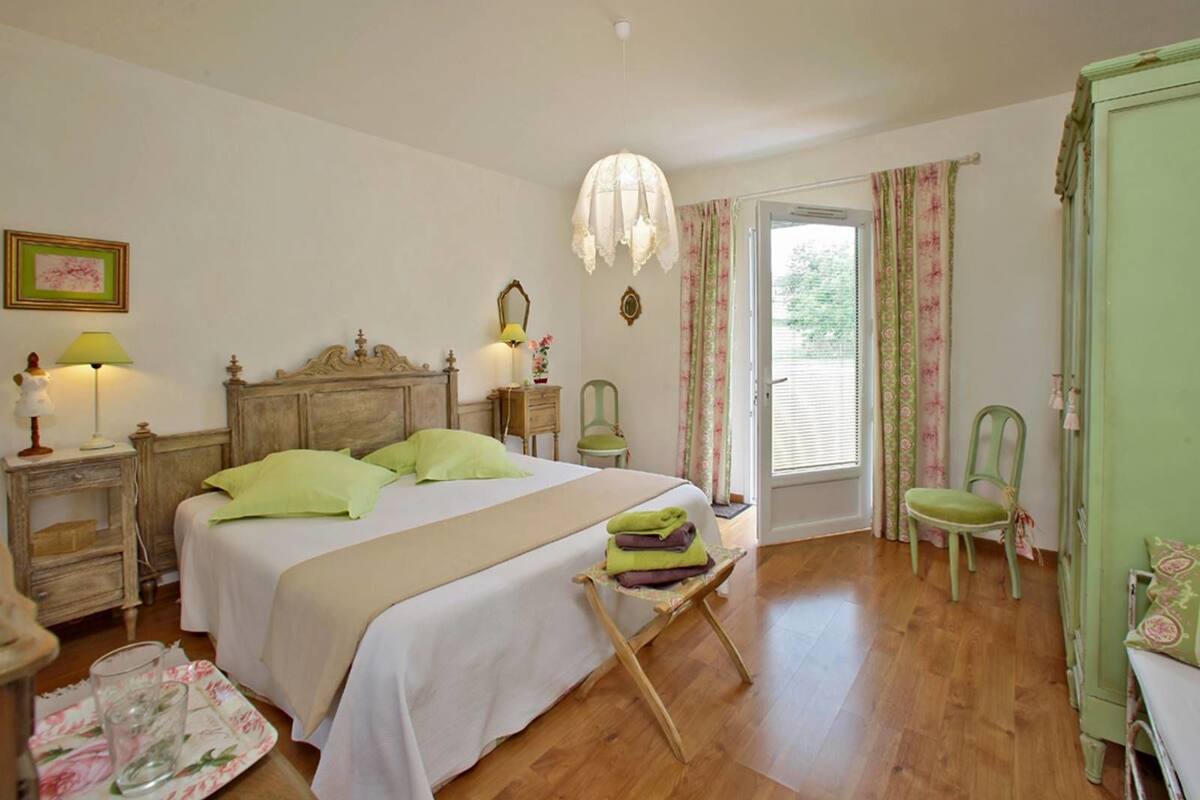 A bedroom with a wooden bed, a nightstand with a lamp, a chair, and a wardrobe.