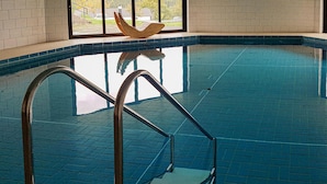 An indoor swimming pool with clear blue tiles, a wooden decorative piece above the pool, and metal pool ladders. - Stunning home in Gerolstein with WiFi (Gerolstein)