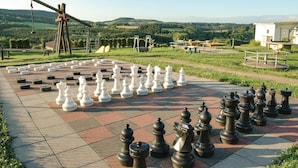 A large outdoor chessboard set up on a paved area with a scenic view of hills and a windmill in the background. - Stunning home in Gerolstein with WiFi (Gerolstein)