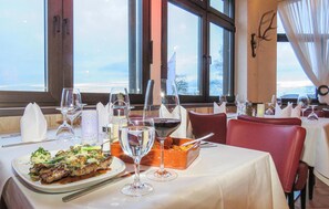 A restaurant table set with wine glasses, a bottle of red wine, and a dish of food. - 3 bedroom amazing home in Gerolstein (Gerolstein)