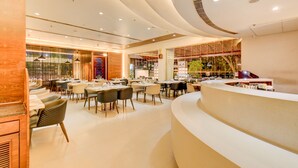 Eine moderne Hotelhalle mit einer gebogenen Rezeption, mehreren Sitzbereichen und großen Fenstern mit Blick ins Innere.