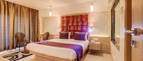 Une chambre d’hôtel moderne avec un grand lit, une table de chevet, une chaise, un miroir et un mur décoré d’un motif.