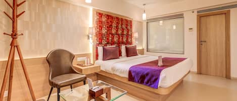 A modern hotel room with a large bed, a desk, a chair, and a tripod.