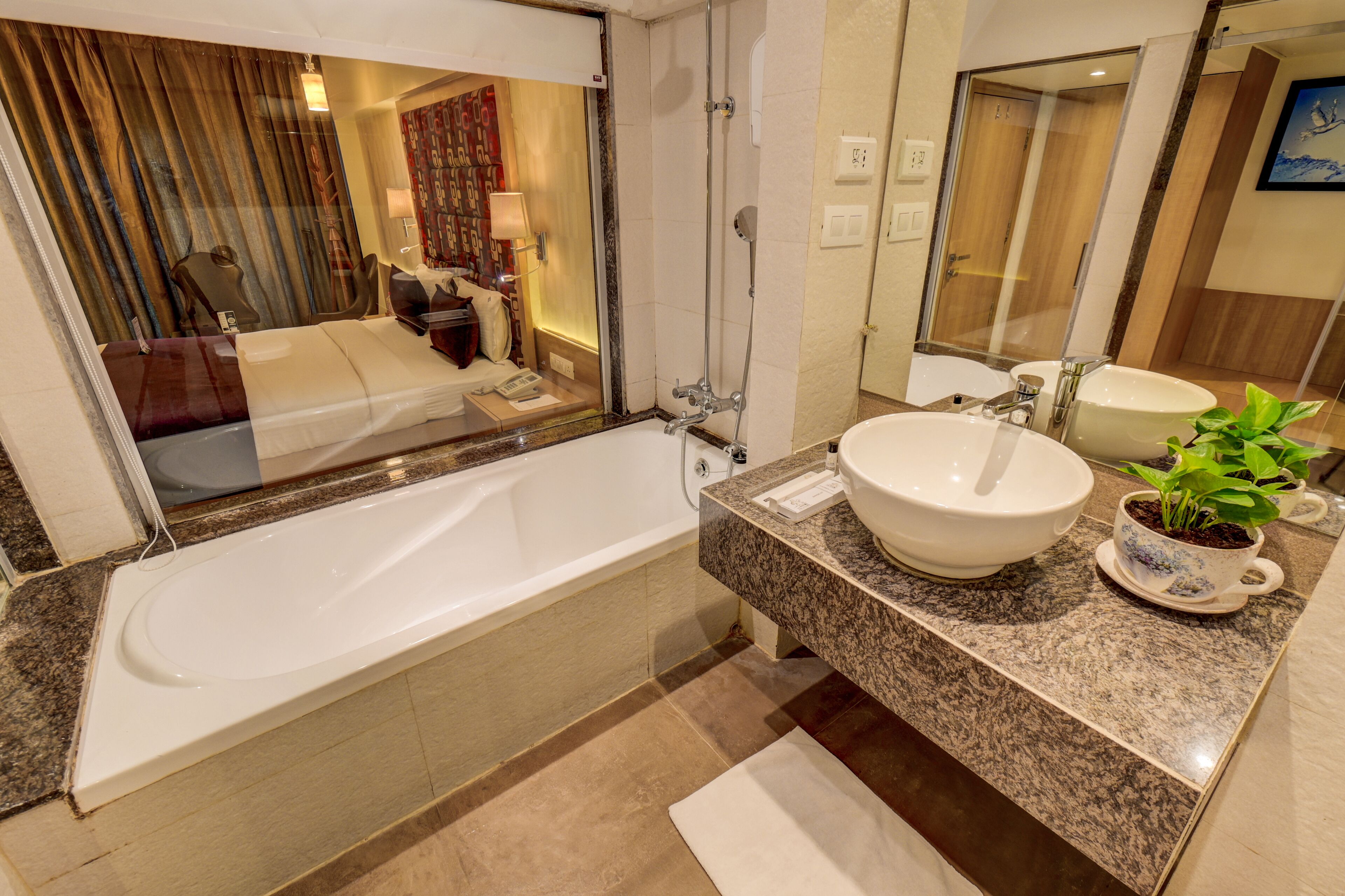 A modern bathroom with a large bathtub, a vanity with a sink and a mirror, and a potted plant.