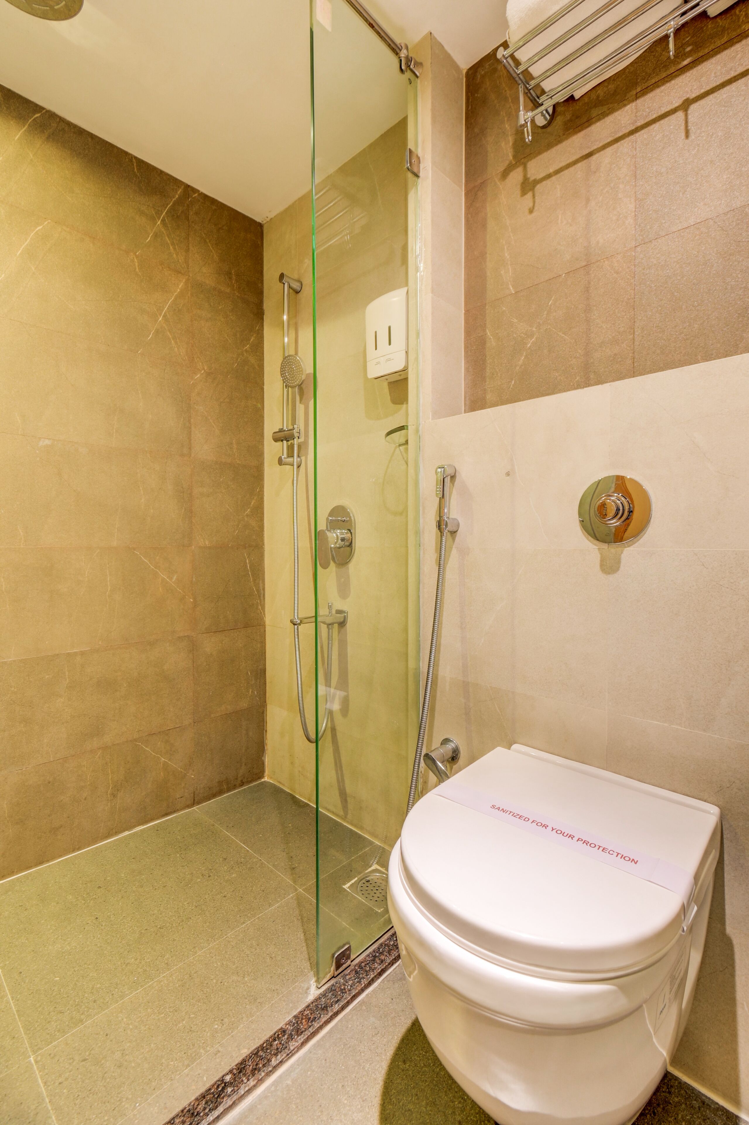 A modern bathroom with a glass-enclosed shower, a toilet, and a towel rack.