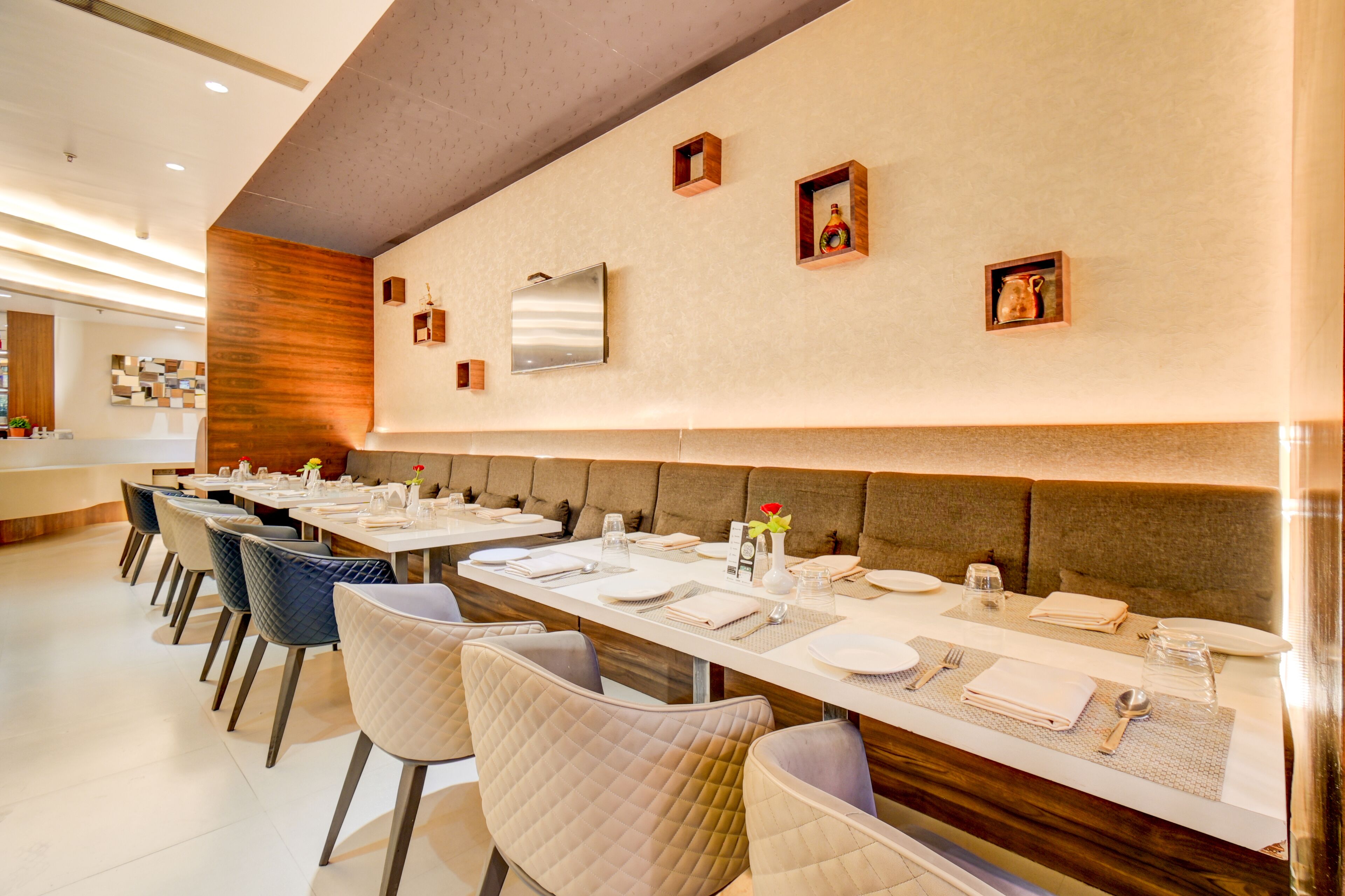 A restaurant with long tables, cushioned chairs, and a modern interior design.