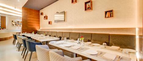 Un restaurante con mesas largas, sillas acolchadas y una decoración interior moderna.