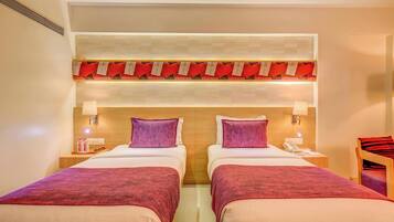 A hotel room with two beds, a wooden headboard, and a red decorative panel above the beds.