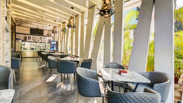 Ein modernes Restaurant mit einer langen Theke, schwarzen Sitzgelegenheiten und hängenden Pendelleuchten.