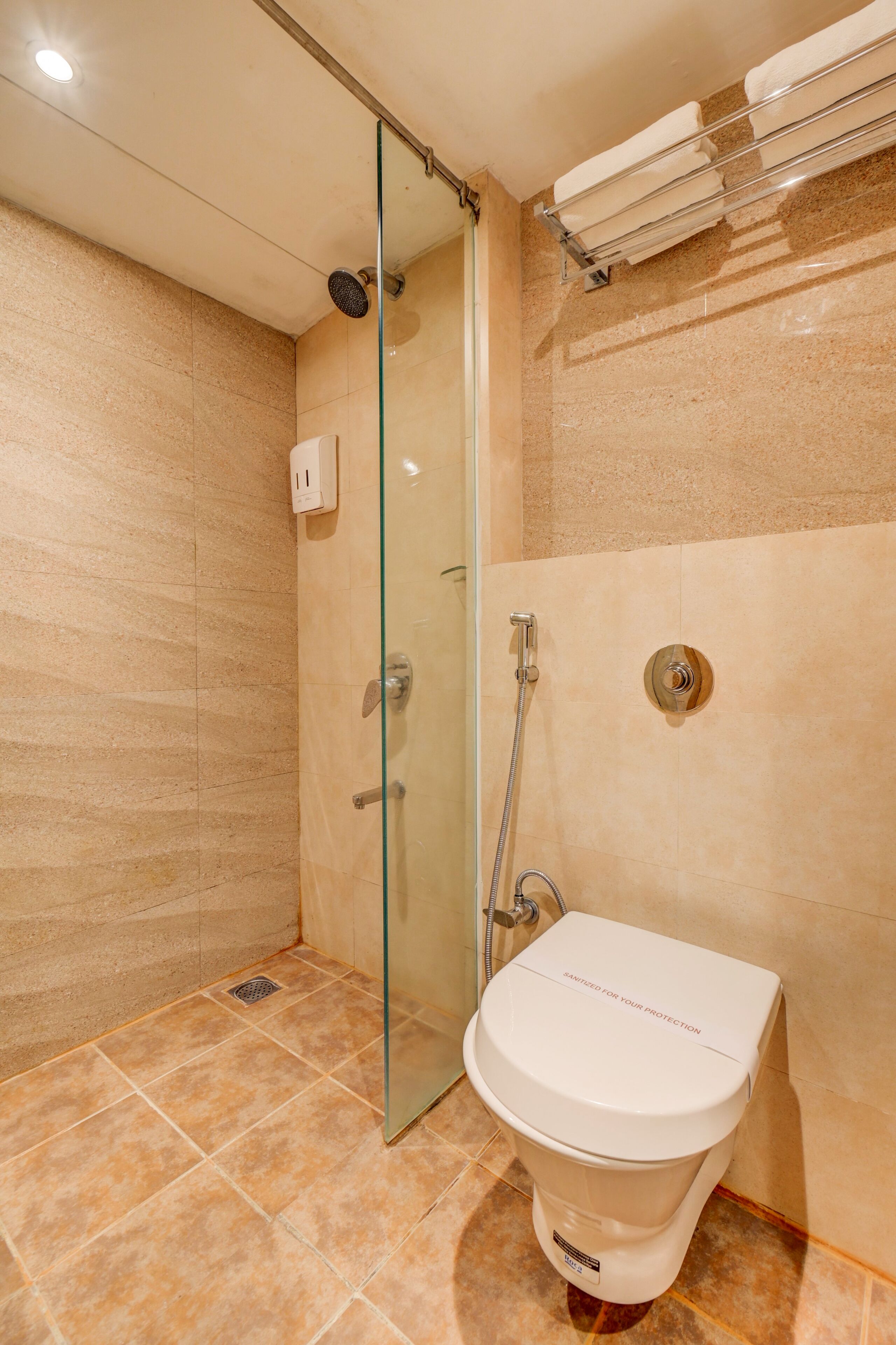 A bathroom with a glass shower enclosure, a toilet, and a towel rack.