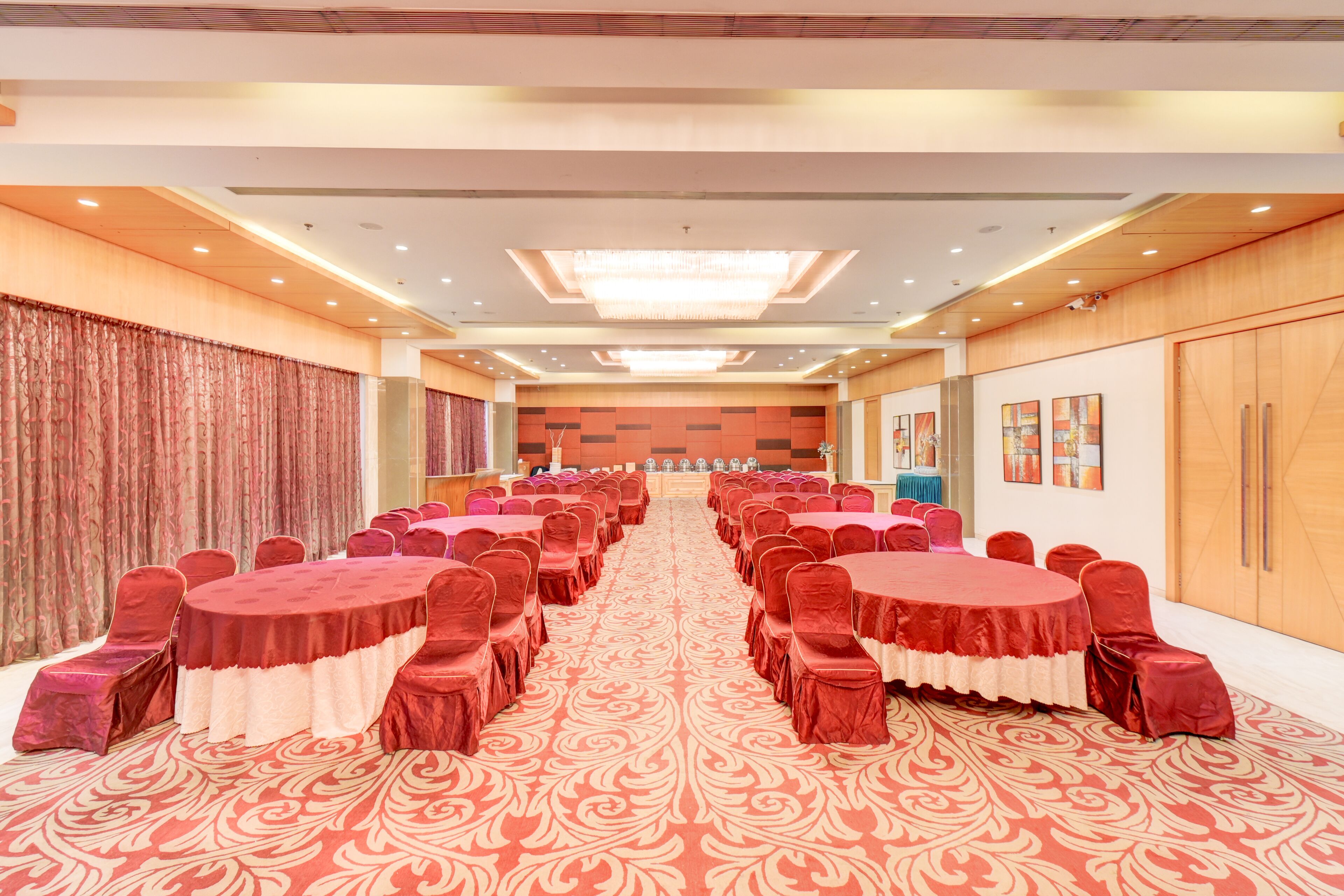 A conference room with round tables and red chairs, a patterned carpet, and wooden paneling on the walls.