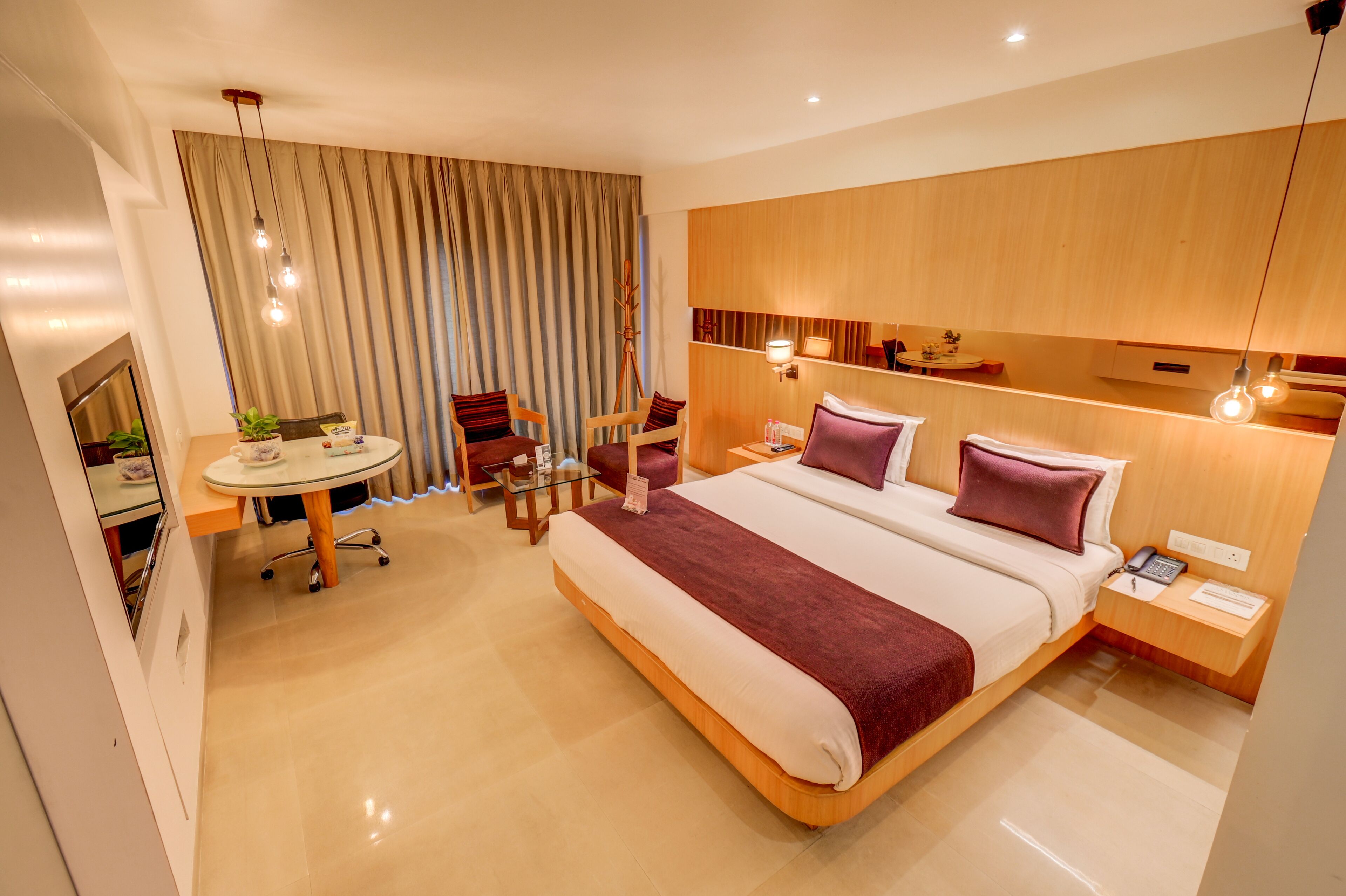 Quarto de hotel moderno com uma cama grande, mesas de cabeceira, uma escrivaninha e uma cadeira.