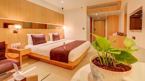 Ein modernes Hotelzimmer mit einem großen Bett, Nachttisch und einer Topfpflanze.