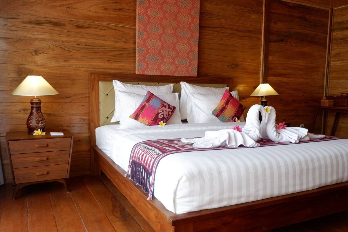 A wooden-paneled room with a bed, two bedside tables, and two lamps.