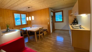 Un interior de madera con comedor, cocina y un sofá rojo.