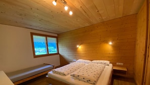 Una habitación con paneles de madera, una cama, un banco y una ventana con vistas.