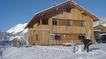 Een houten chalet met veel ramen, een schuin dak en een met sneeuw bedekte grond.