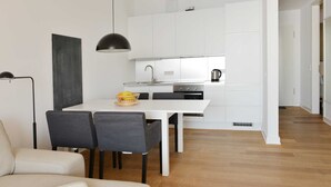 Una cocina moderna con armarios blancos, una lámpara colgante negra y una mesa de comedor con sillas.