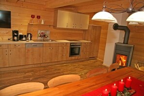 Enjoy meals in this well-equipped kitchen with a central island and modern stove, complemented by a dining area with a wooden table and chairs.