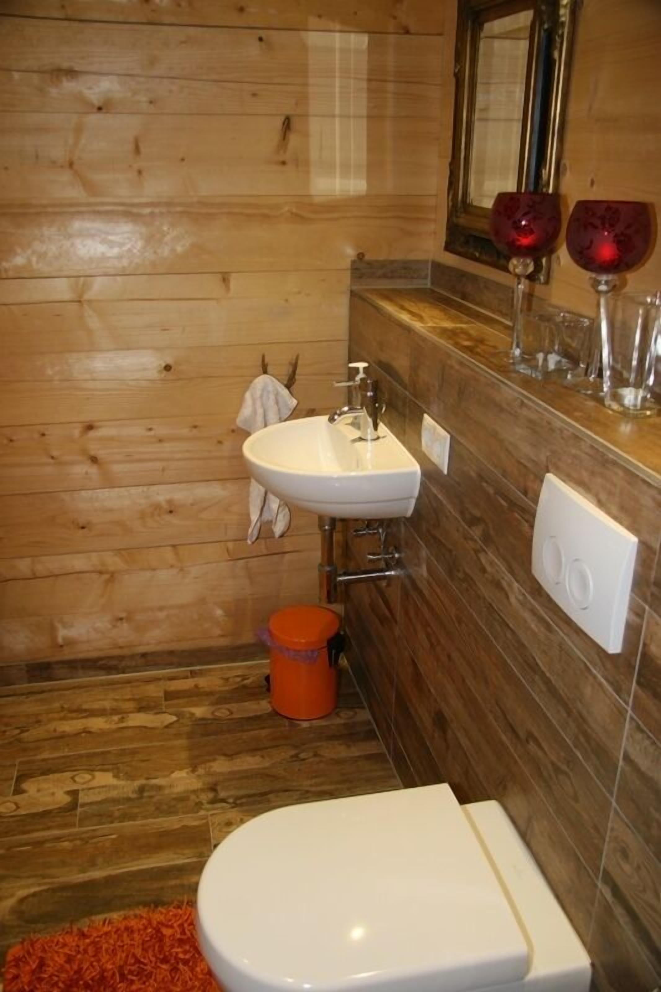 A wooden-paneled bathroom with a white sink, a toilet, and a mirror above the sink.