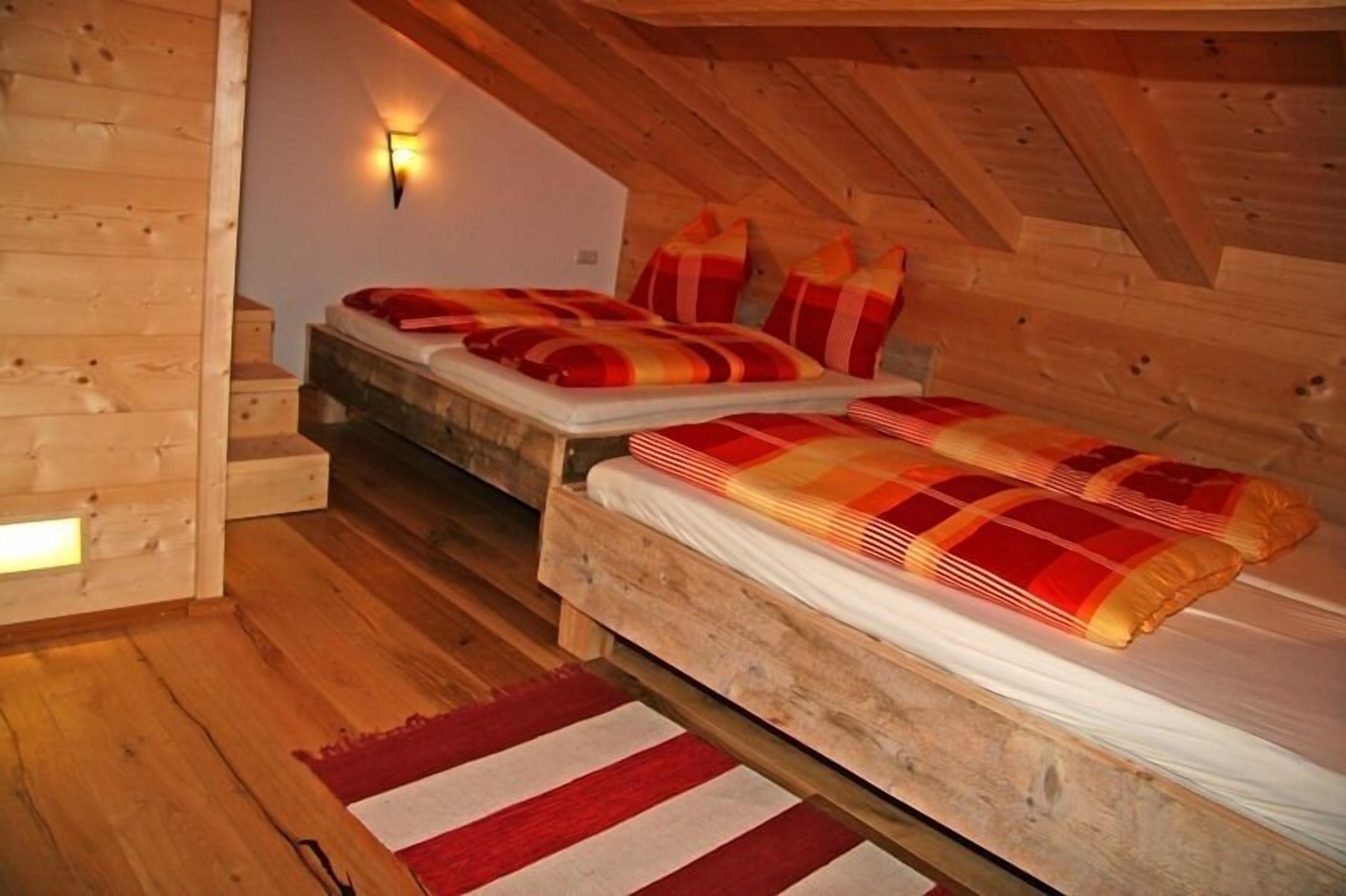 Una camera da letto mansardata accogliente, con due letti, pareti in legno e soffitto spiovente.