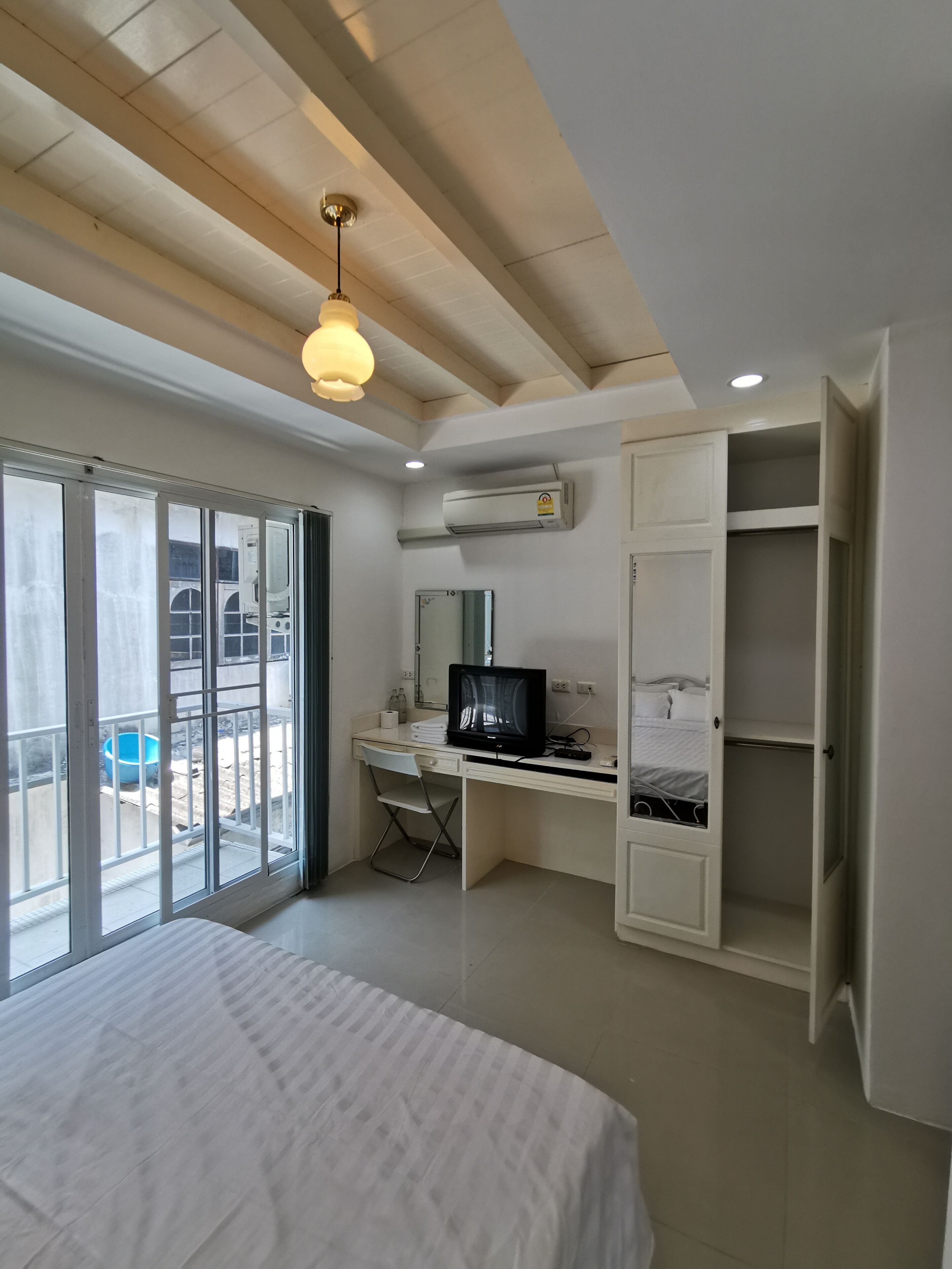 Une chambre à coucher avec un lit, un bureau avec un ordinateur, une chaise et une armoire.