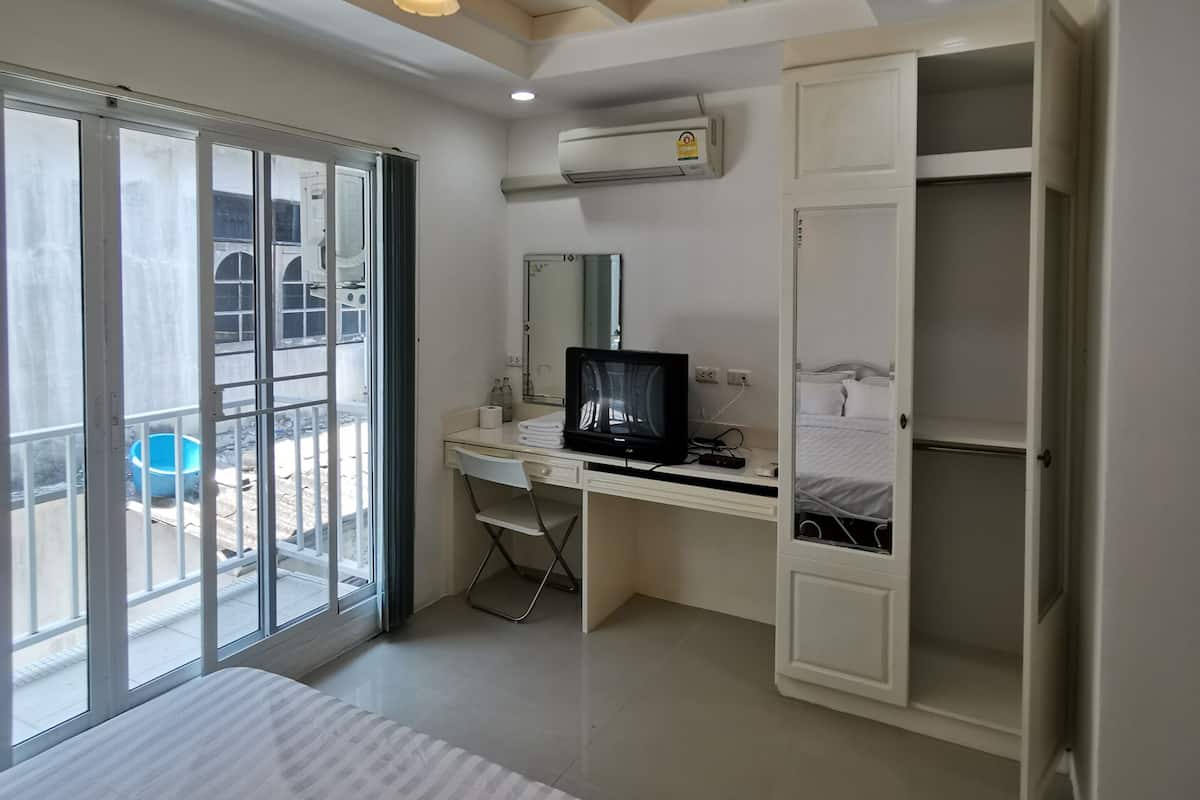 A bedroom with a bed, a desk with a computer, a chair, and a wardrobe.