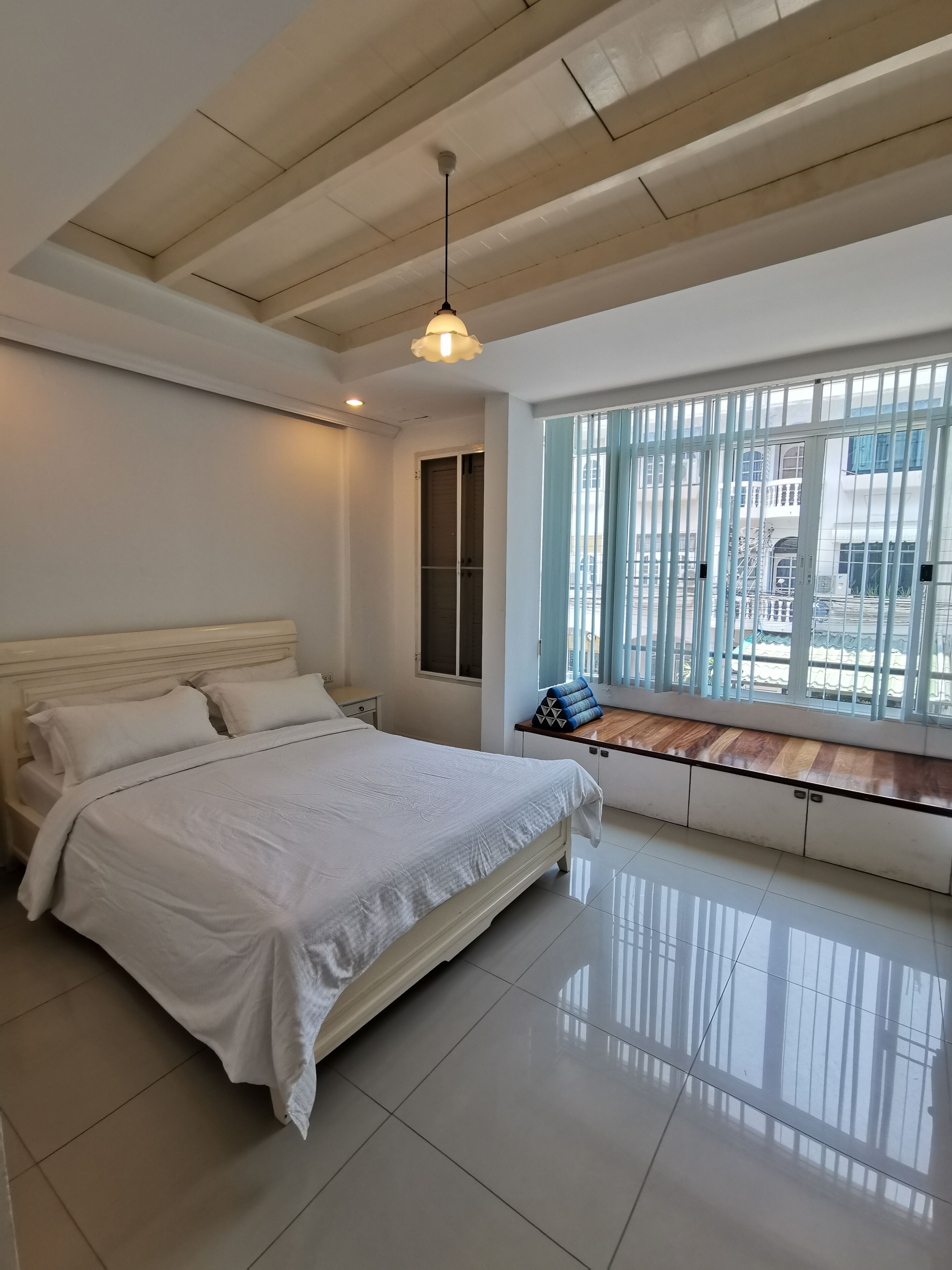 Une chambre à coucher avec un lit, une fenêtre donnant sur un beau paysage, un luminaire au plafond et un plafond en bois.