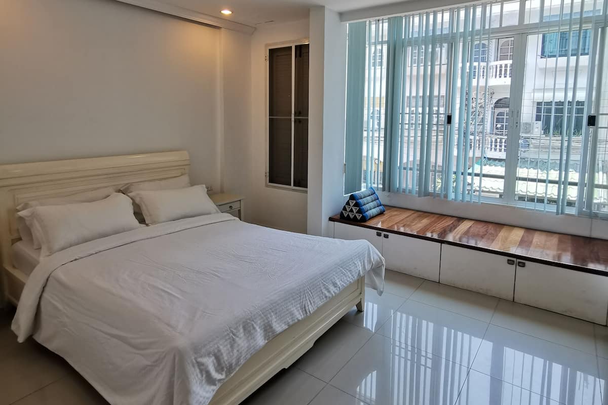 A bedroom with a bed, a window with a view, a ceiling light, and a wooden ceiling.