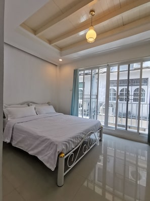 A bedroom with a bed, a window with curtains, a ceiling light, and a view of the outside. - Ratchada-Sutthisan Hotel and Longstay (Bangkok)