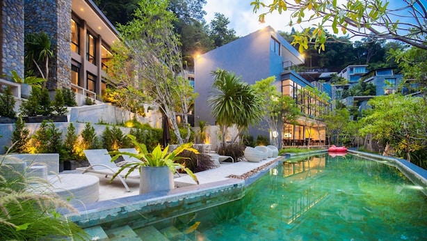 Un hôtel moderne doté d’une piscine, d’un espace extérieur aménagé et d’un jardin luxuriant.