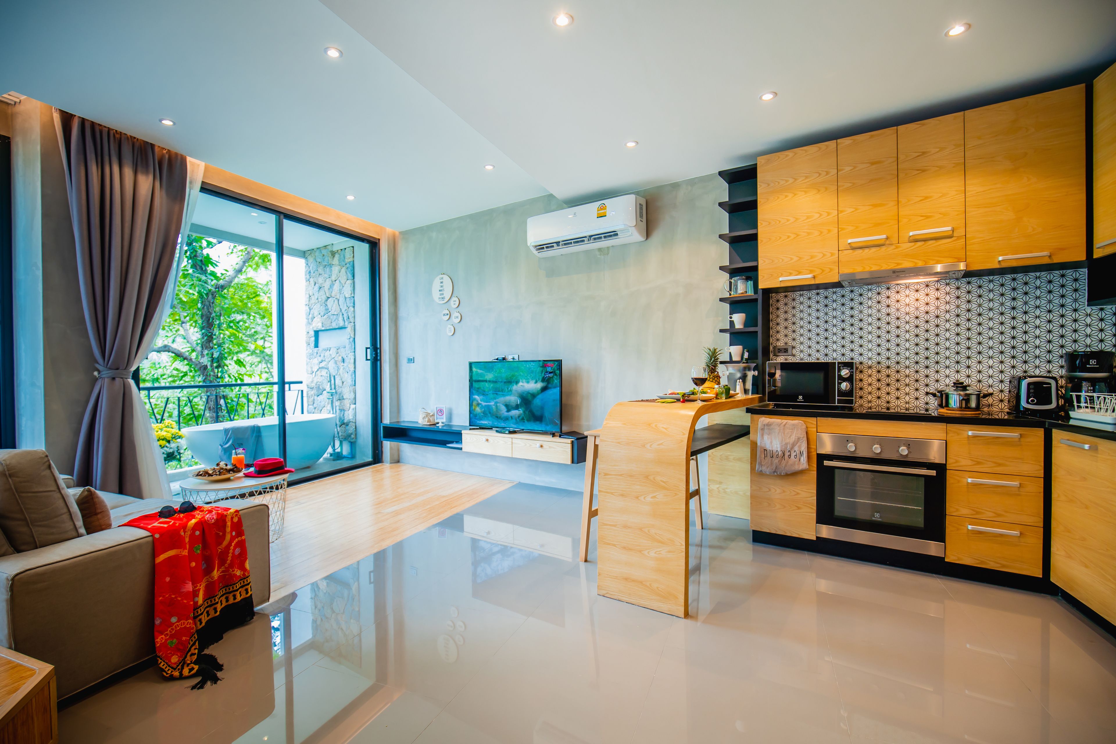 A modern kitchen with wooden cabinets, a built-in oven, and a large window overlooking a balcony.