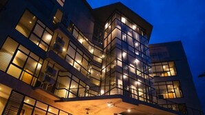 Un hôtel moderne à plusieurs étages, doté d’une façade en verre, de nombreux balcons et d’un vaste espace extérieur aménagé pour se détendre.
