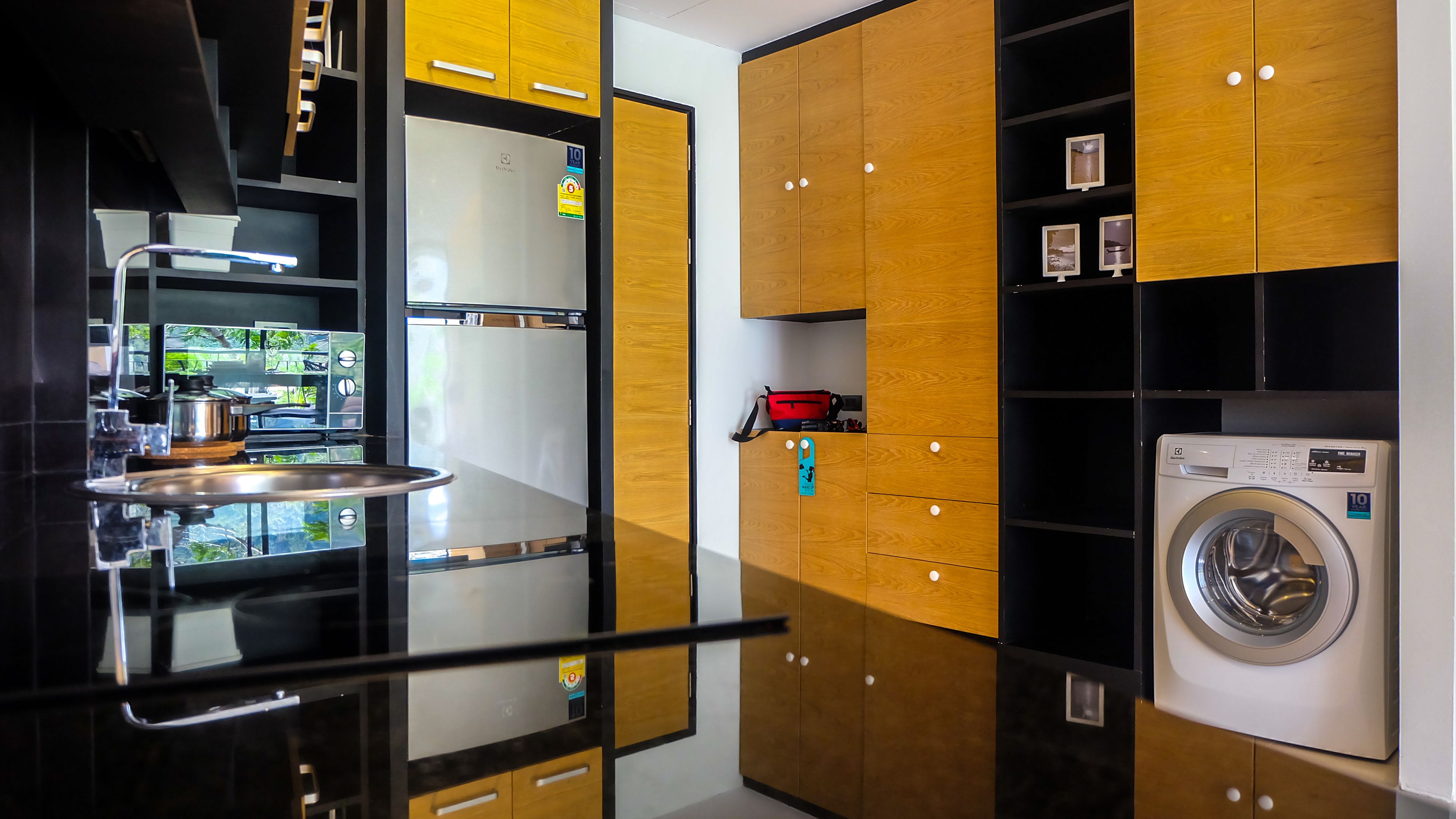 A modern kitchen with a stainless steel refrigerator, a sink, and a washing machine.